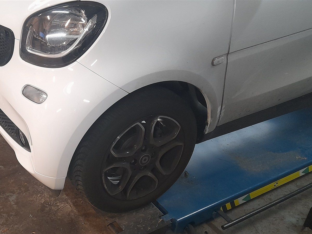 Weißer Kleinwagen auf der Hebebühne in der Werkstatt